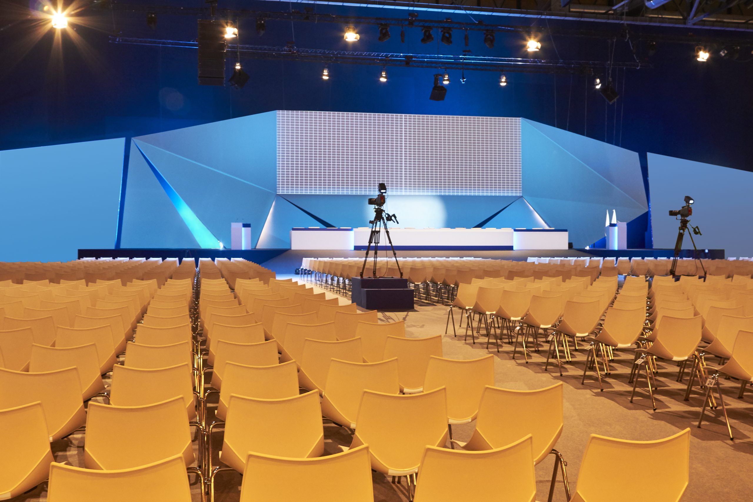Vergadering dienst. Evenementzaal ingericht met professionele beeld- en geluidsoplossingen voor vergaderingen, inclusief podium, stoelen en camerainstallaties.