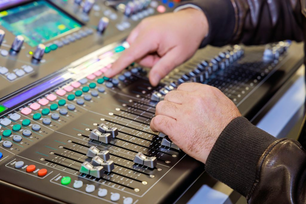 Technicus bedient professionele mengtafel voor audio tijdens een live evenement, voor optimale geluidskwaliteit en naadloze productie. Bedoeld voor professionele streaming met beeld en geluid