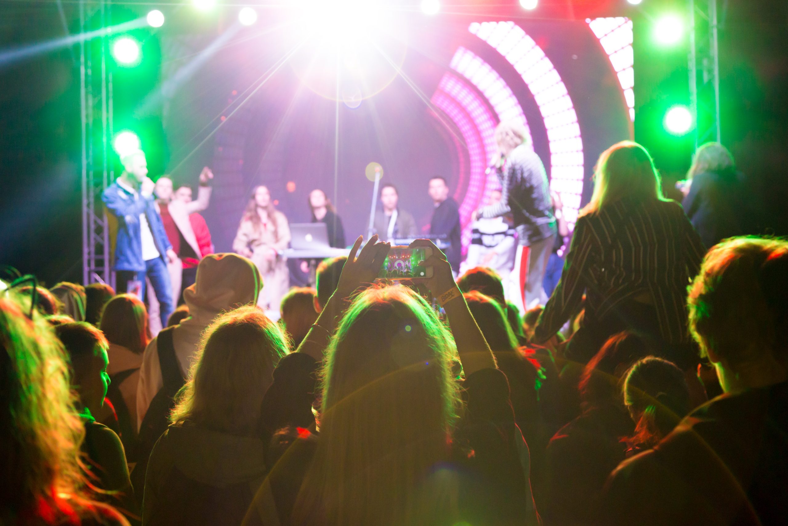 Artiesten dienst. Publiek geniet van een live optreden met professionele beeld- en geluidsoplossingen voor artiesten, inclusief kleurrijke lichtshows op het podium.