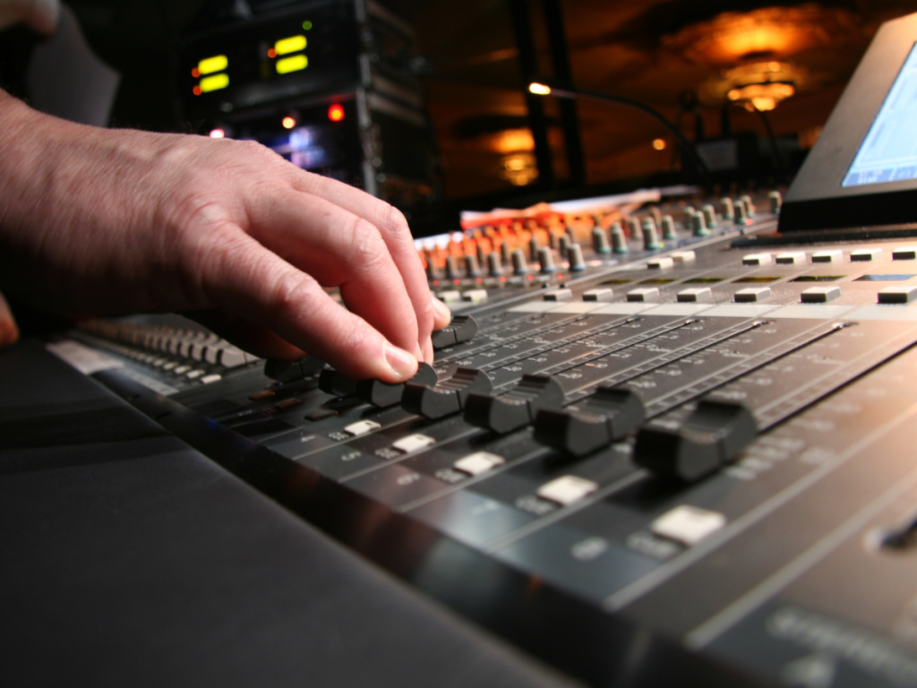 Hand van een technicus die een geluidsmengpaneel afstemt voor een audiovisuele productie evenement. Hoogwaardige apparatuur zorgt voor perfect geluid.