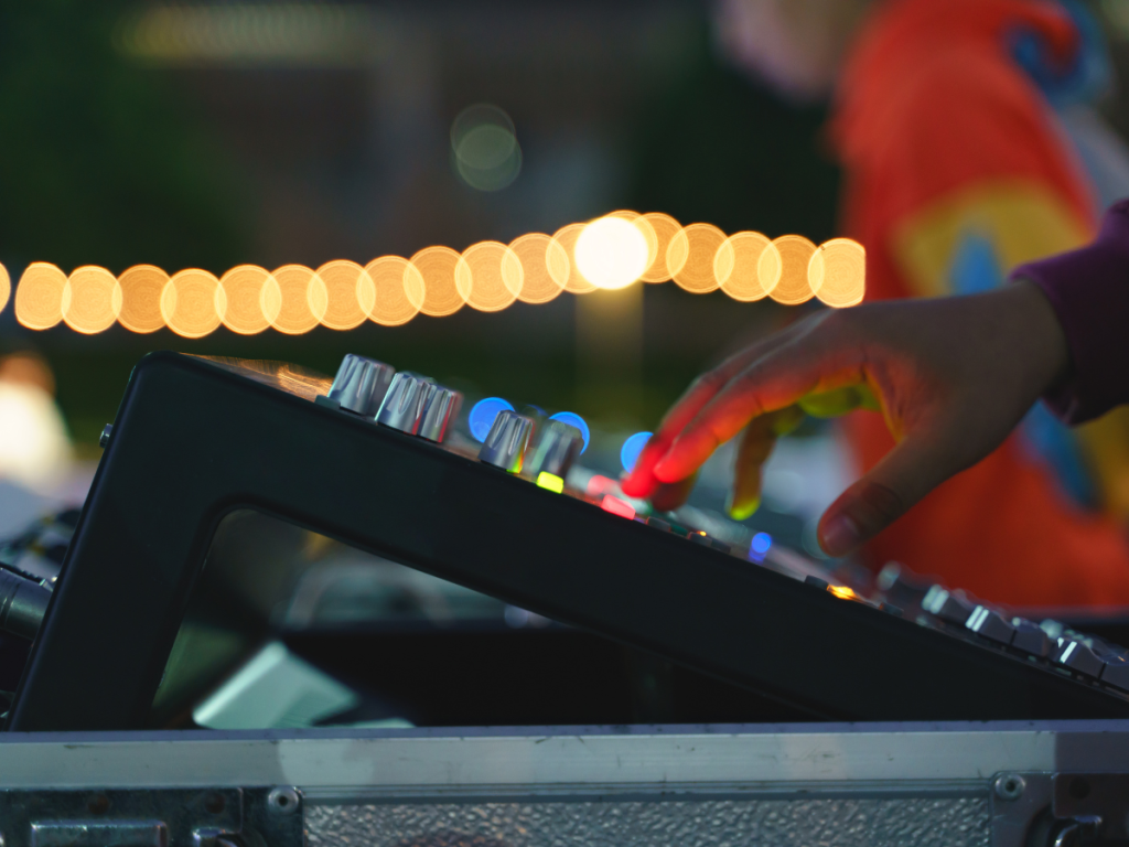 Hand bedient een geluidsmixer tijdens een live evenement, ondersteund door professionele licht- en geluidsverhuur voor een vlekkeloze uitvoering.