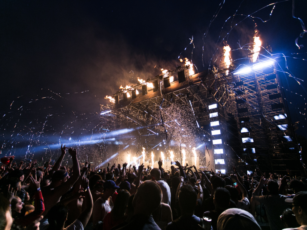 Een spectaculair muziekfestival met een uitbundig publiek, vuurshows en indrukwekkende lichteffecten. Het podium is verlicht met dynamische LED-verlichting en krachtige spotlights, wat zorgt voor een meeslepende sfeer. Professionele licht- en geluidsoplossingen zijn essentieel om een evenement als dit tot een succes te maken, waarbij het publiek volledig opgaat in de ervaring.