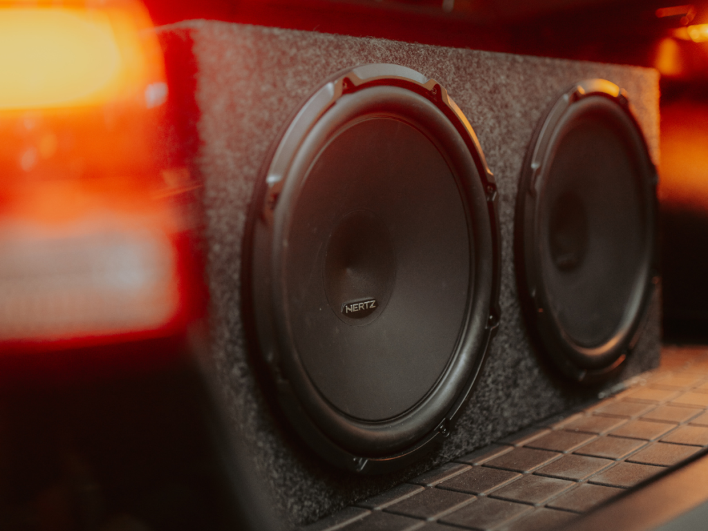 Zwarte subwoofers in een beklede behuizing in een auto met warme rode verlichting
