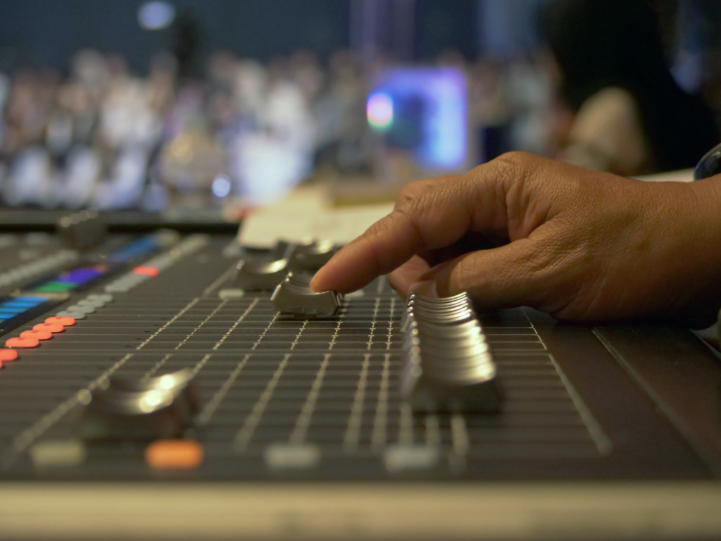 Hand van technicus stelt audio in op professioneel mengpaneel tijdens live event