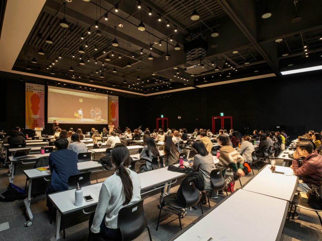 Conferentiezaal met publiek en spreker op podium tijdens zakelijke presentatie