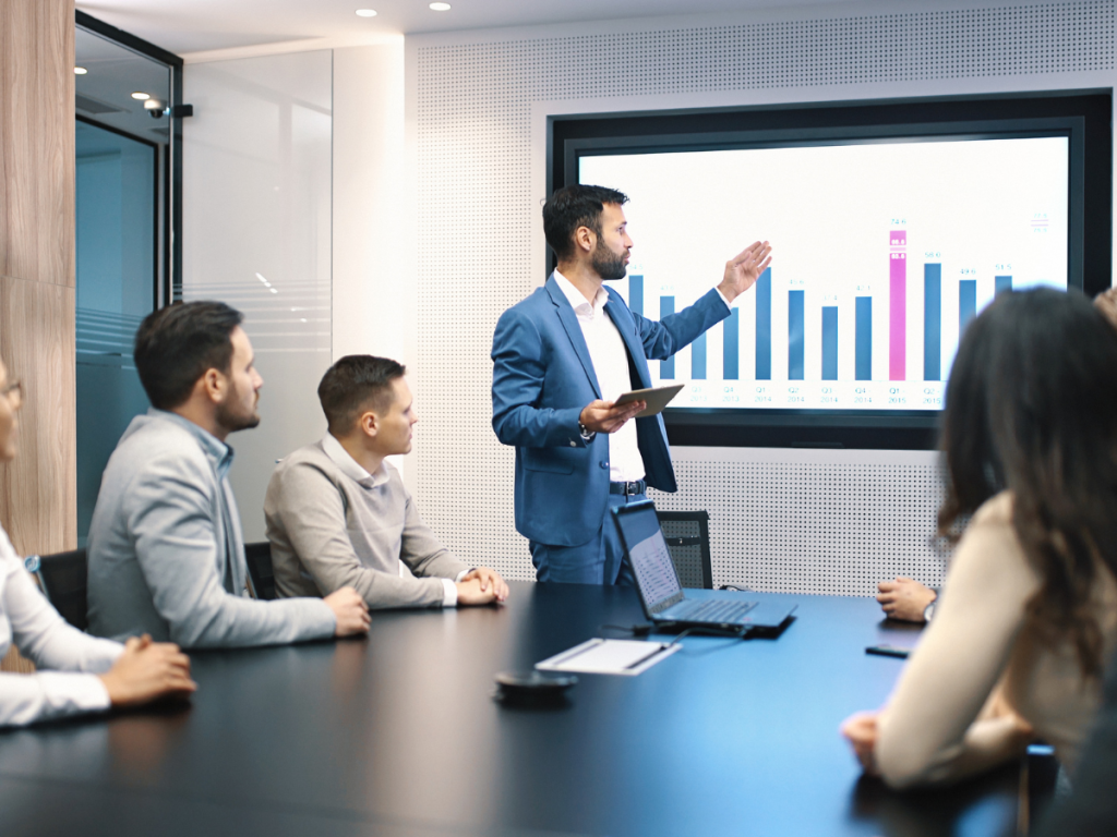 Zakenman presenteert grafiek op groot scherm tijdens boardroom-vergadering