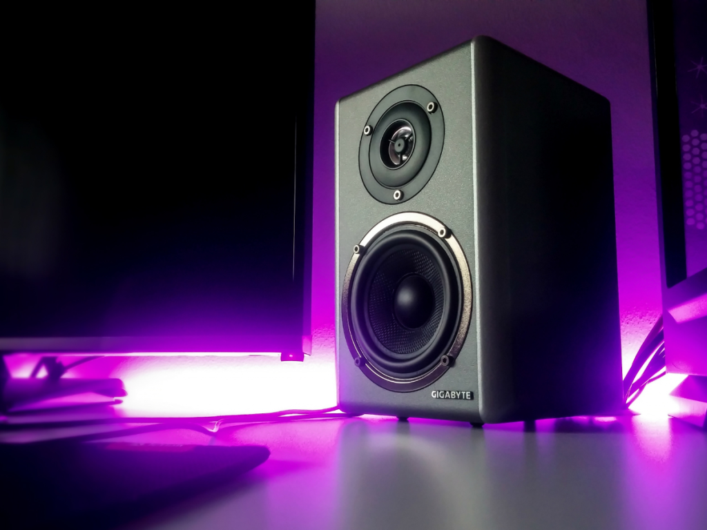 Monitor speaker met paarse ledverlichting op een bureau tussen twee schermen
